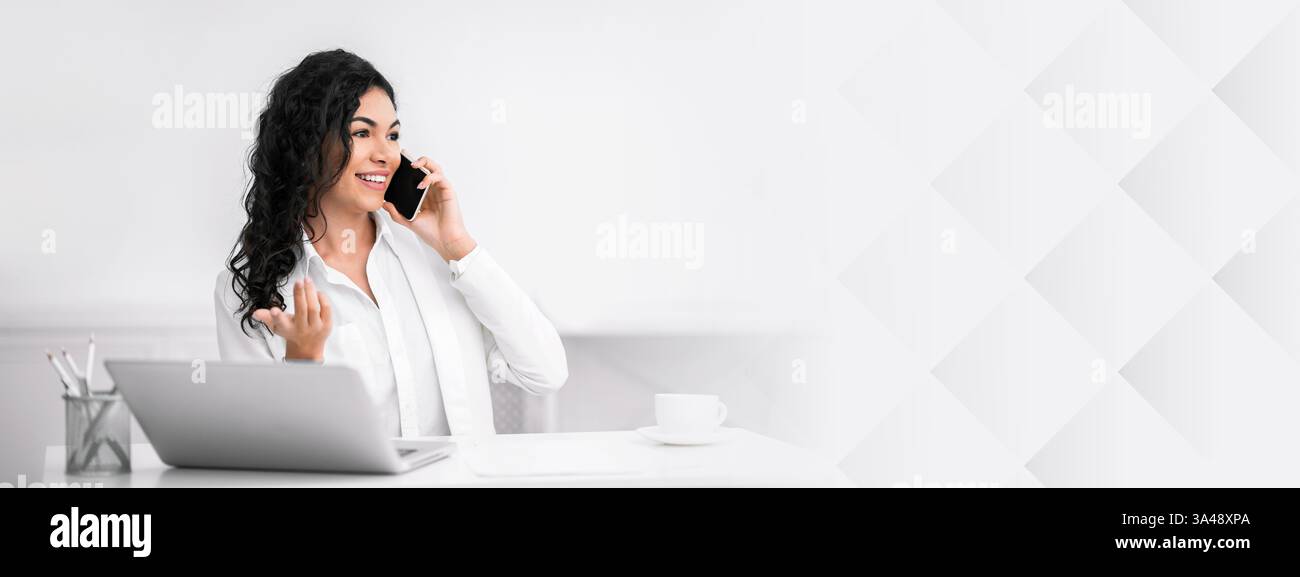 Smiling hispanic lady talking on the phone at office Stock Photo