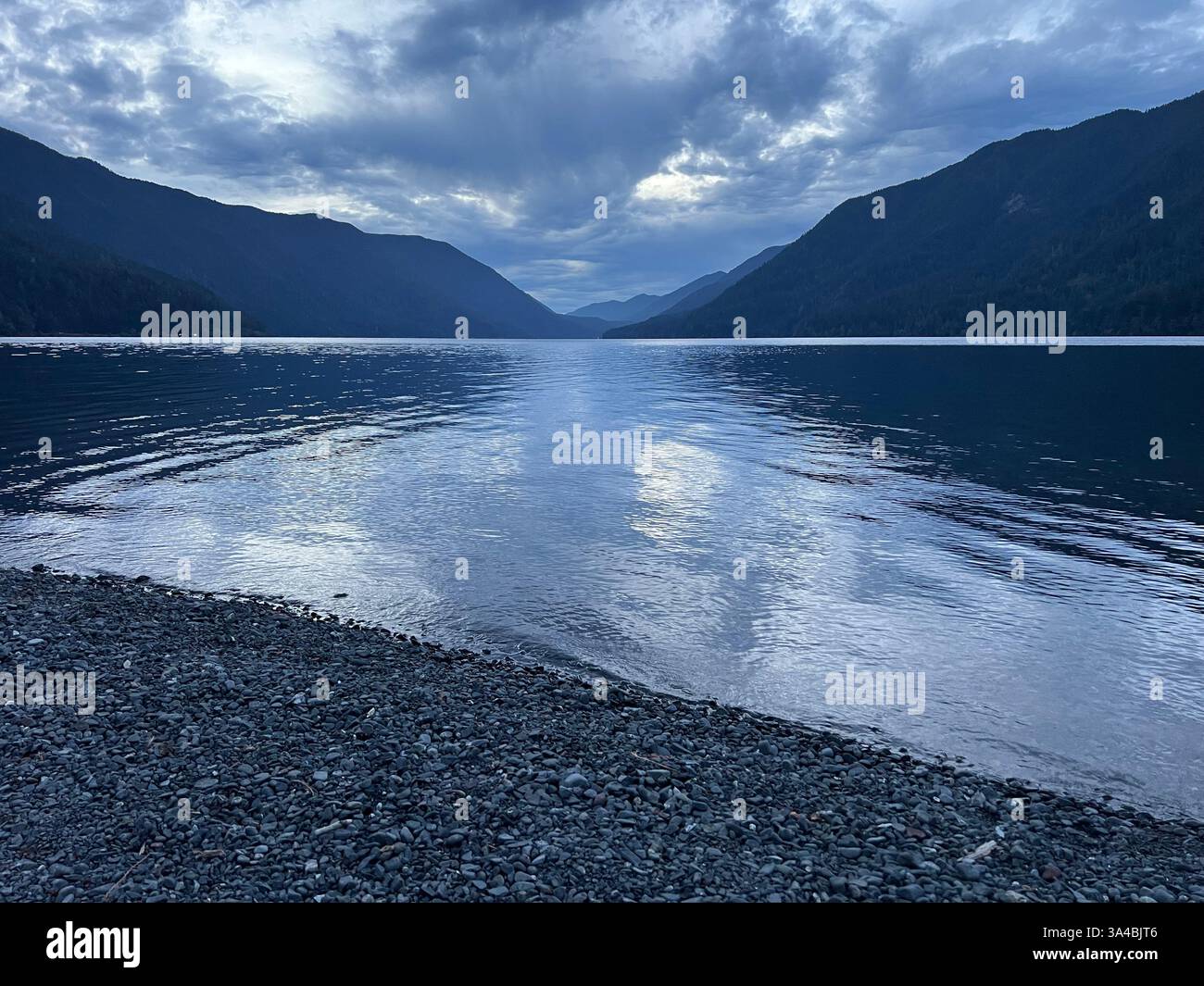 Evening view of the Lake Crescent in Olympic National Park Washington. Heavy white clouds in the sky reflecting in the water of the lake. Mountains - Smartphone Captured Stock Image