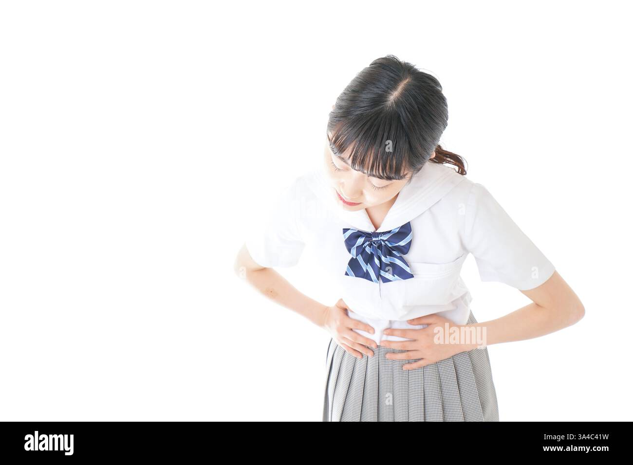 Schoolgirl in school uniform suffering from menstrual cramps Stock
