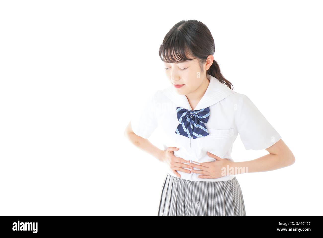 Schoolgirl in school uniform suffering from menstrual cramps Stock