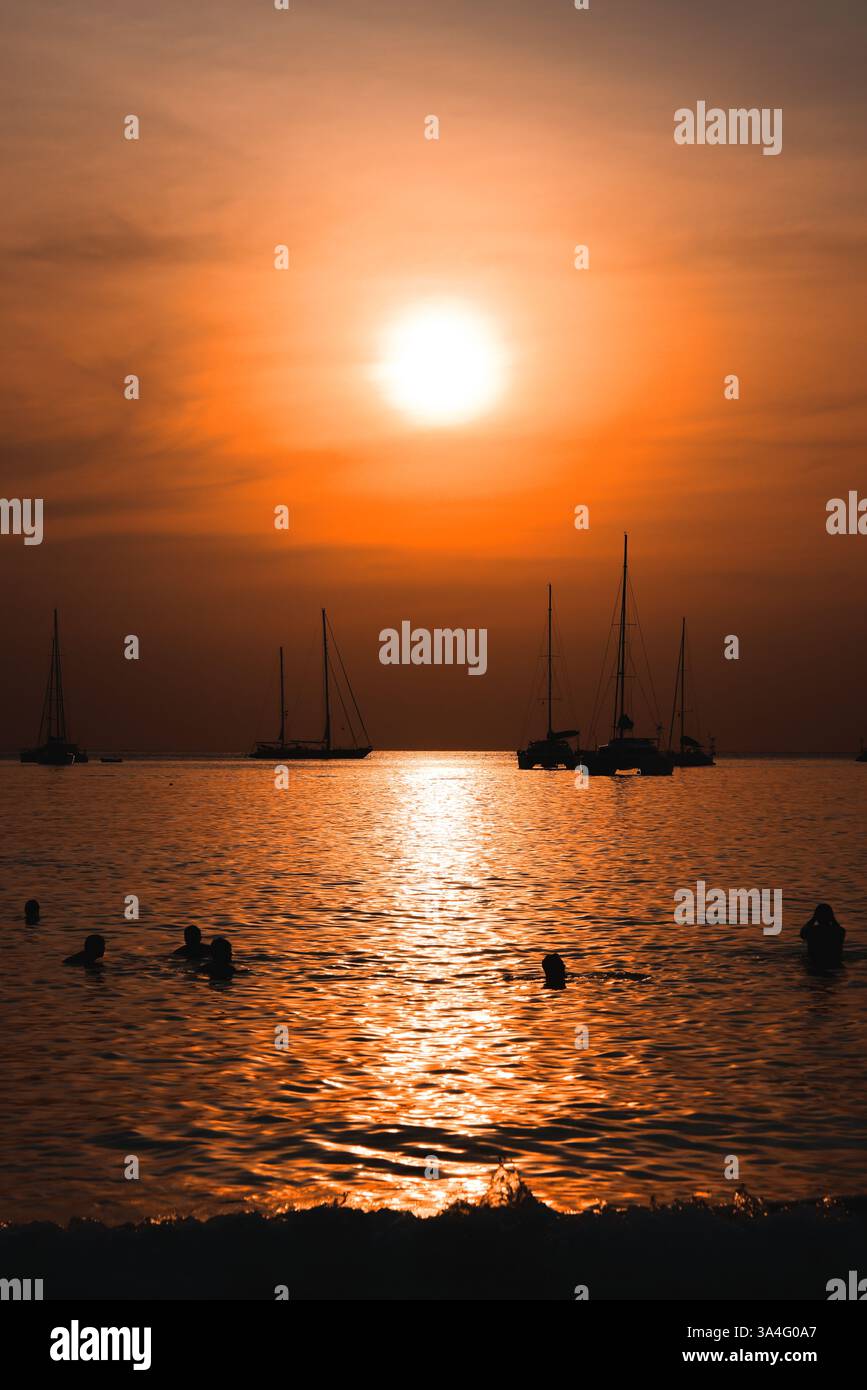 A stunning sunset casts vibrant colors over the ocean with silhouetted ...