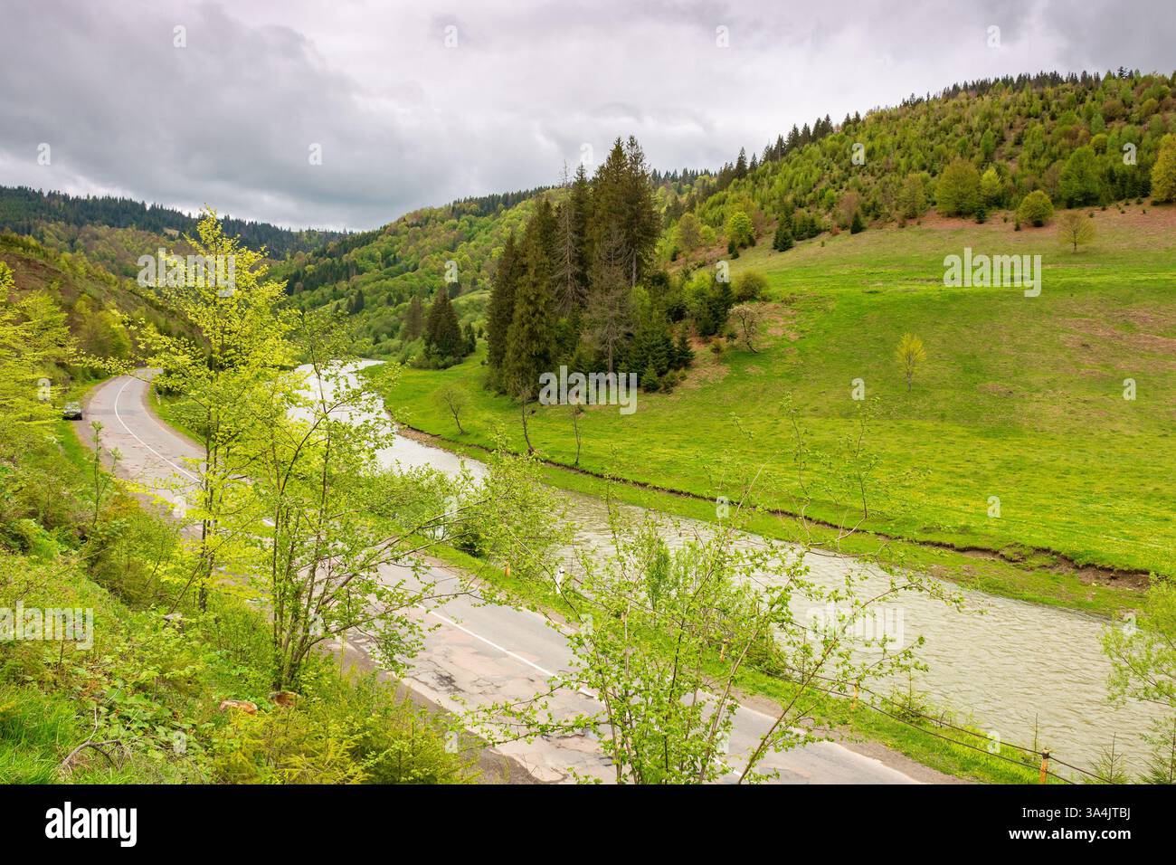 mountain landscape with road along river. beautiful scenery in spring. nature background for travel. green outdoor with forest on the hill. natural en Stock Photo