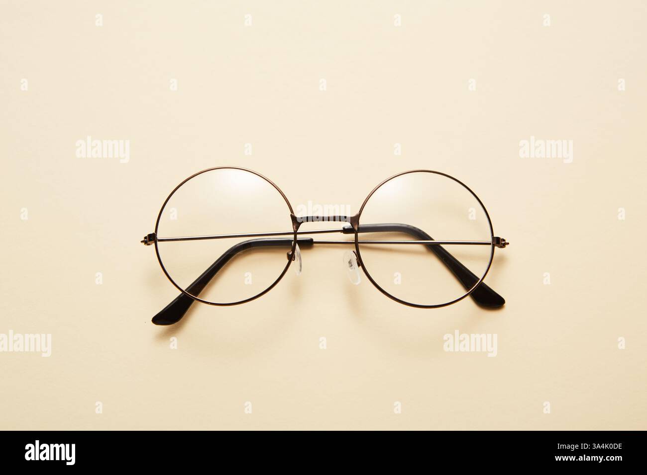 Glasses in round thin metal frame isolated on beige surface. Stock Photo