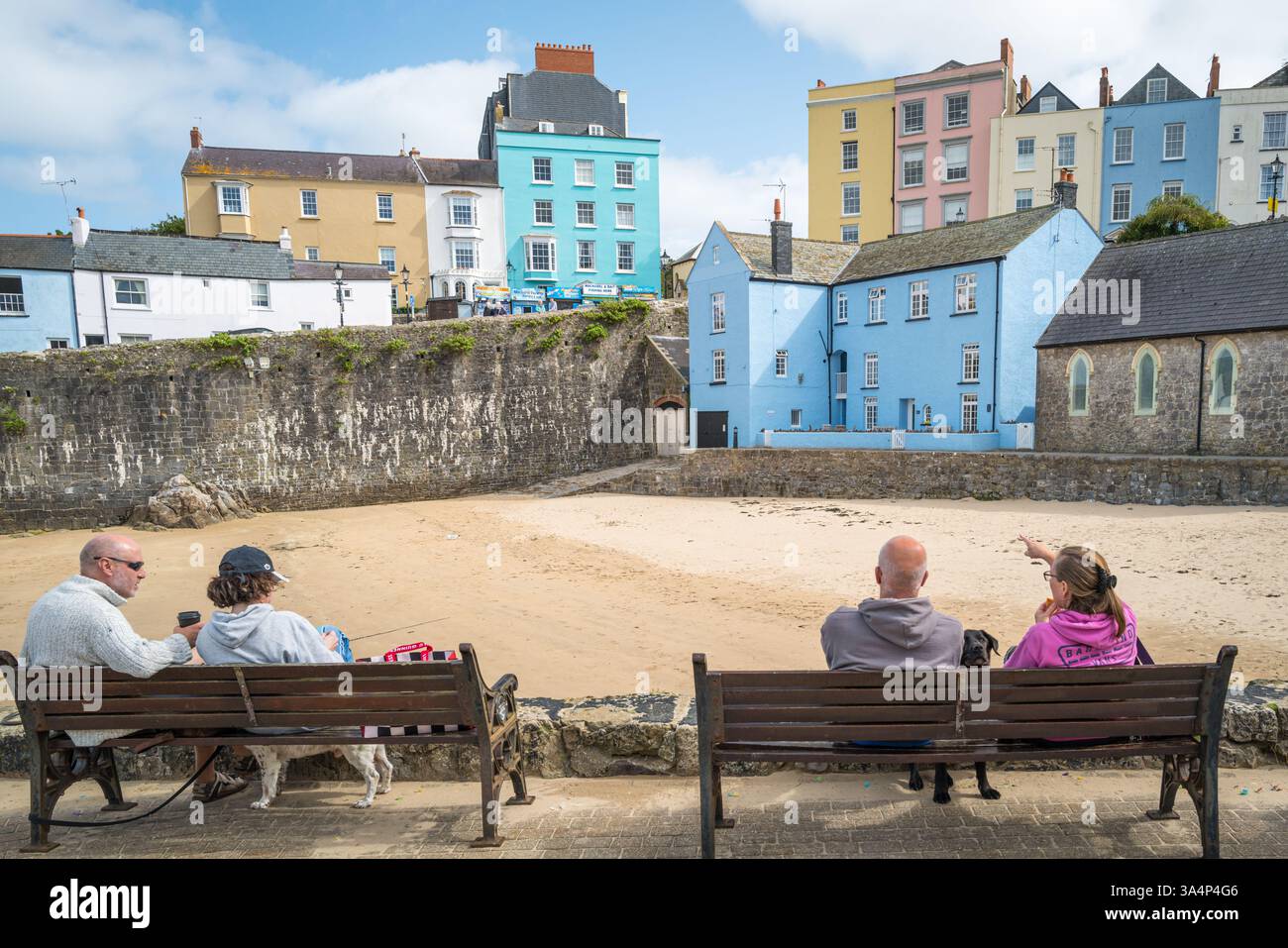 People sitting overlooking the harbour at Tenby in South Wales, UK. Stock Photo