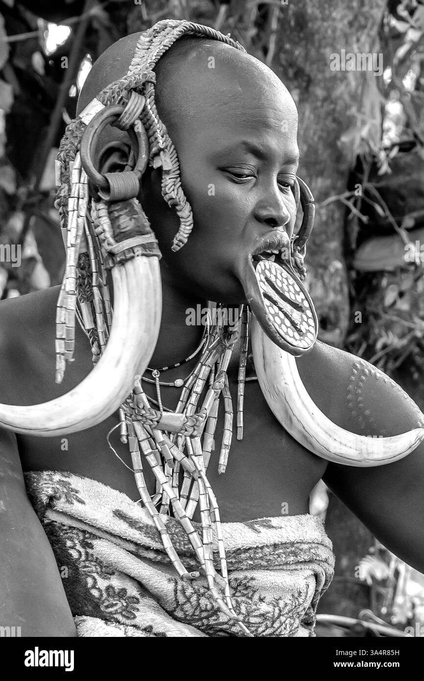 Ethiopia, a woman from the Mursi tribe with beautiful head decoration sits in front of her hut. Omo Valley, Jinka, 21/02/2024 Stock Photo