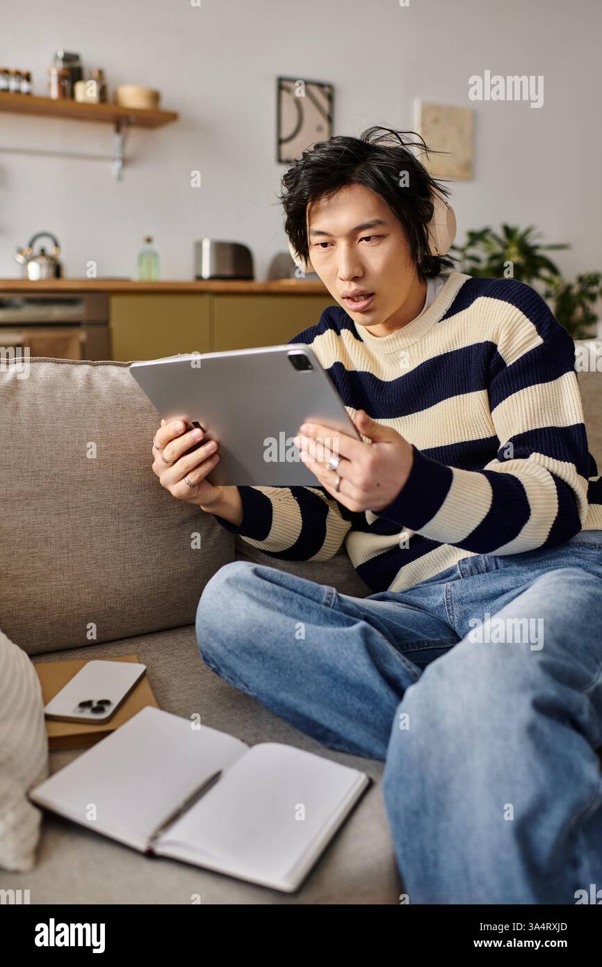 A handsome young man engages with his tablet, focusing intently on ...