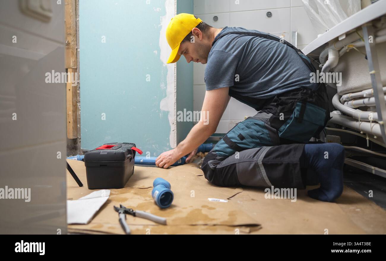 Man assembling plumbing pipes in the bathroom. Stock Photo