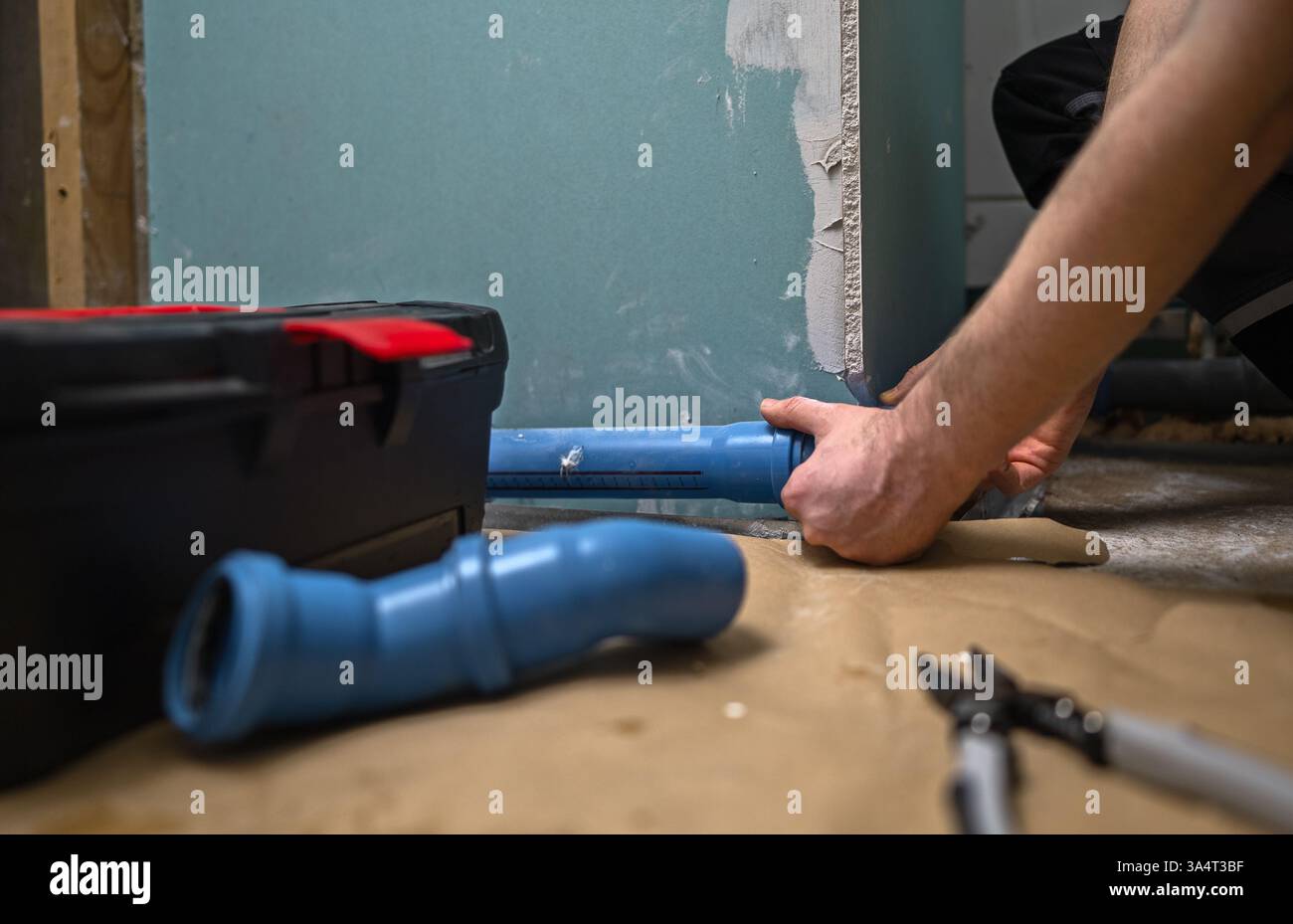 Man assembling plumbing pipes in the bathroom. Stock Photo
