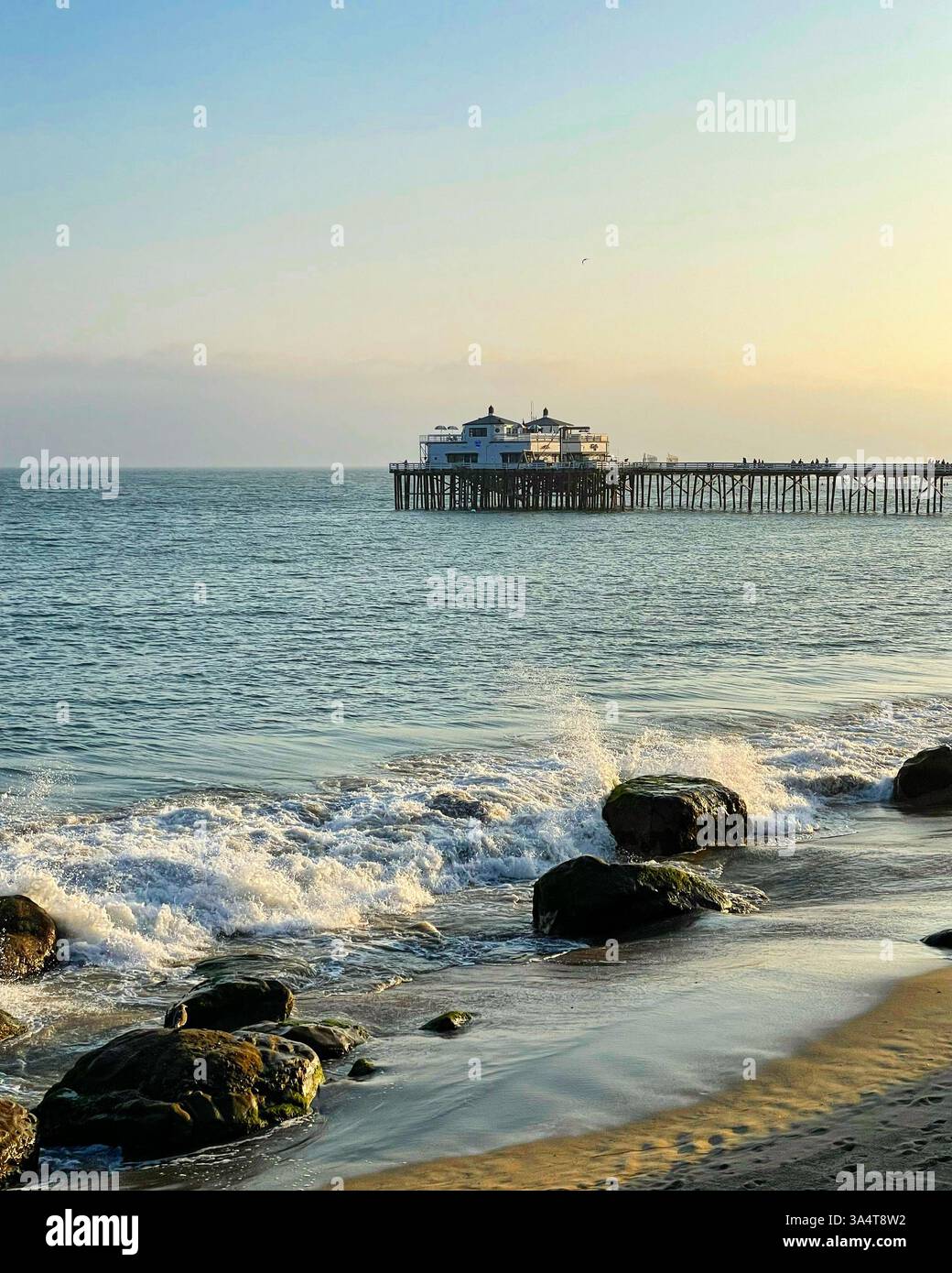 breaking waves by rocks with pier - Smartphone Captured Stock Image