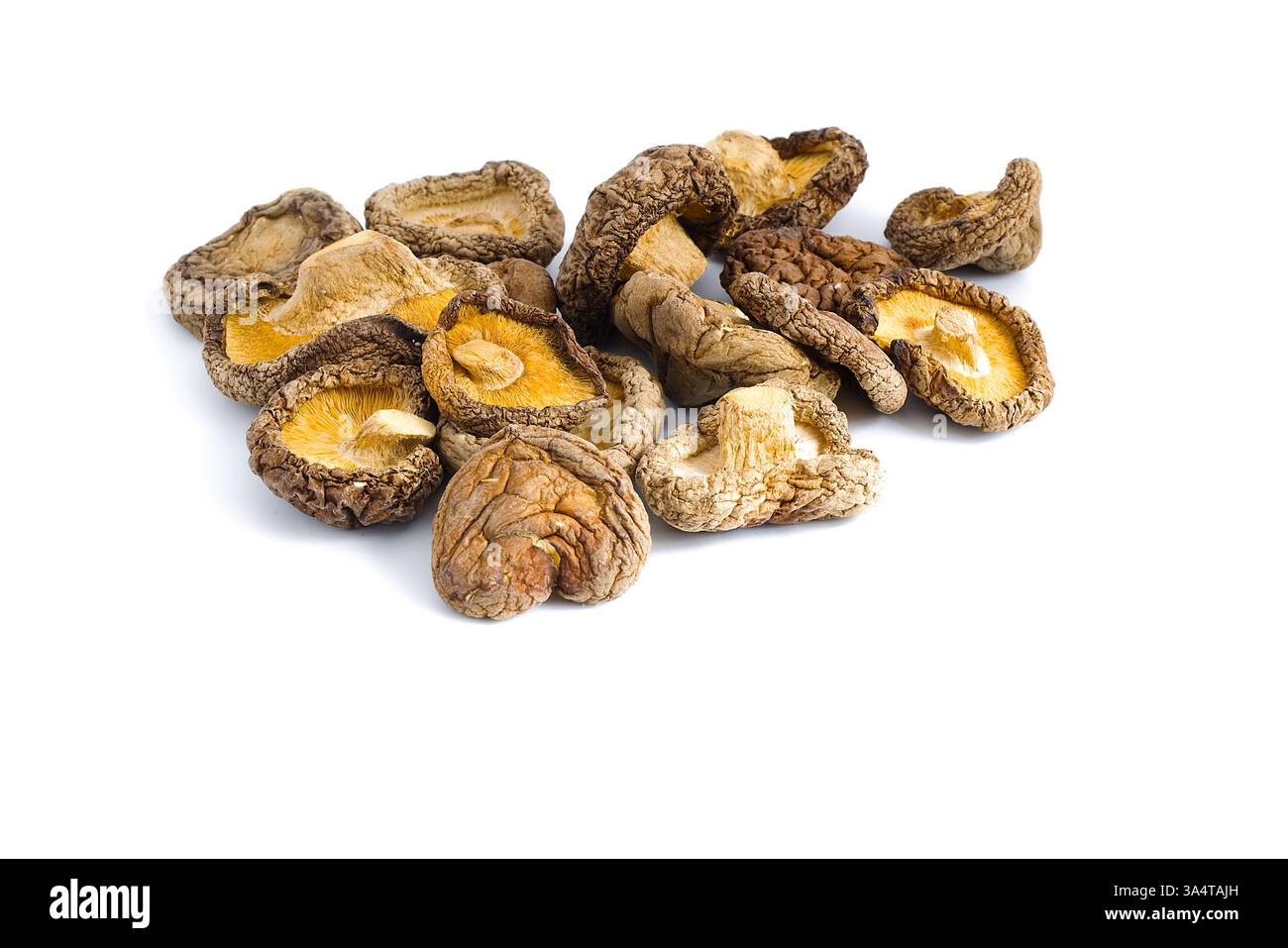 This photograph of dried shiitake mushrooms on white emphasizes their textured, rustic surfaces and rich umami tones, capturing the essence of a tradi Stock Photo