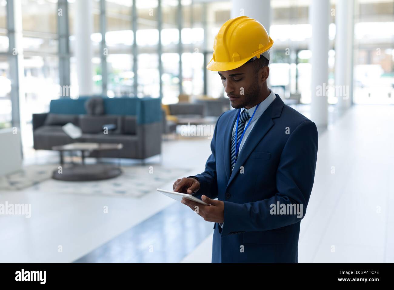 Engineer in suit using tablet in modern office building, focused on work, copy space Stock Photo
