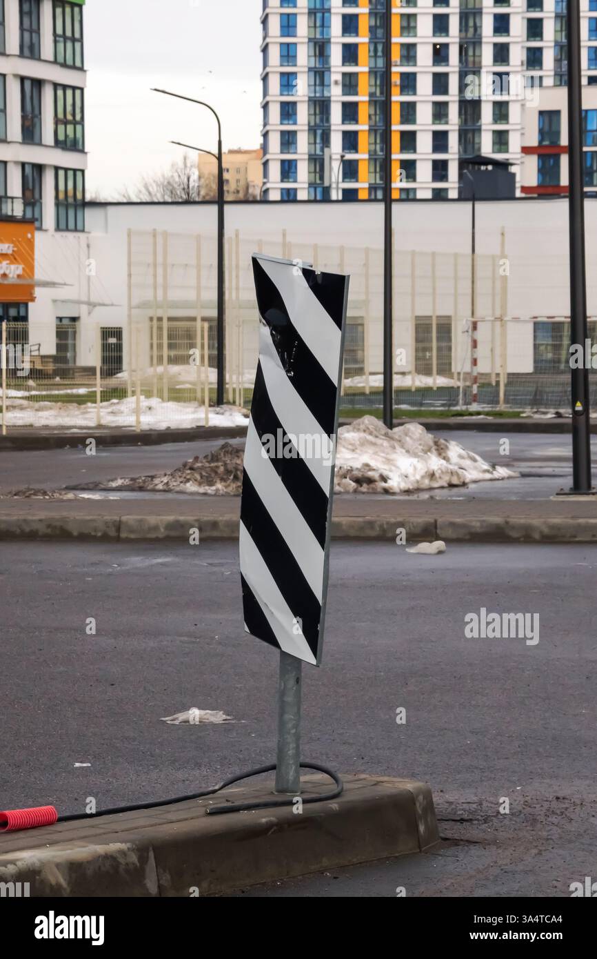 On the side of the road stands a pole that is striped in black and ...