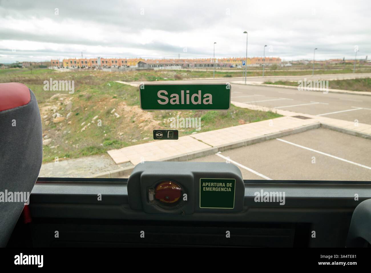 A sign in Spanish that says "Salida" (Exit) and a device with a sign that says "apertura de emergencia" (Emergency Exit) on the window of a passenger Stock Photo