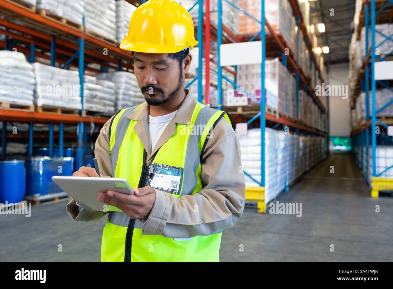 Warehouse worker in safety vest using tablet for inventory management, copy space Stock Photo