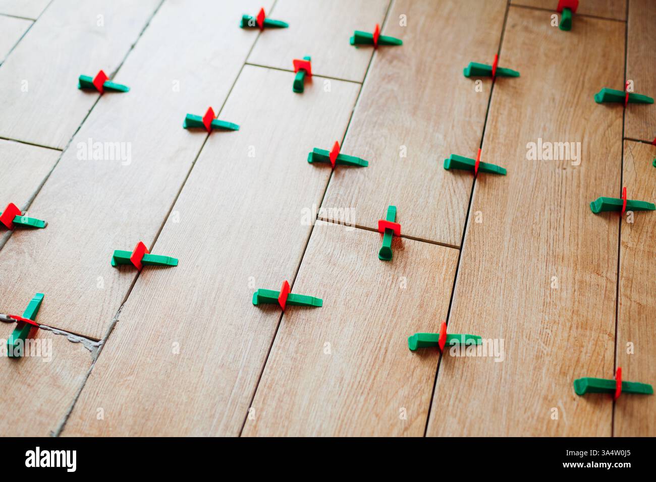Tile leveling system with plastic clips and wedges. Wood effect narrow tiles installed on floor. Renovation of home Stock Photo