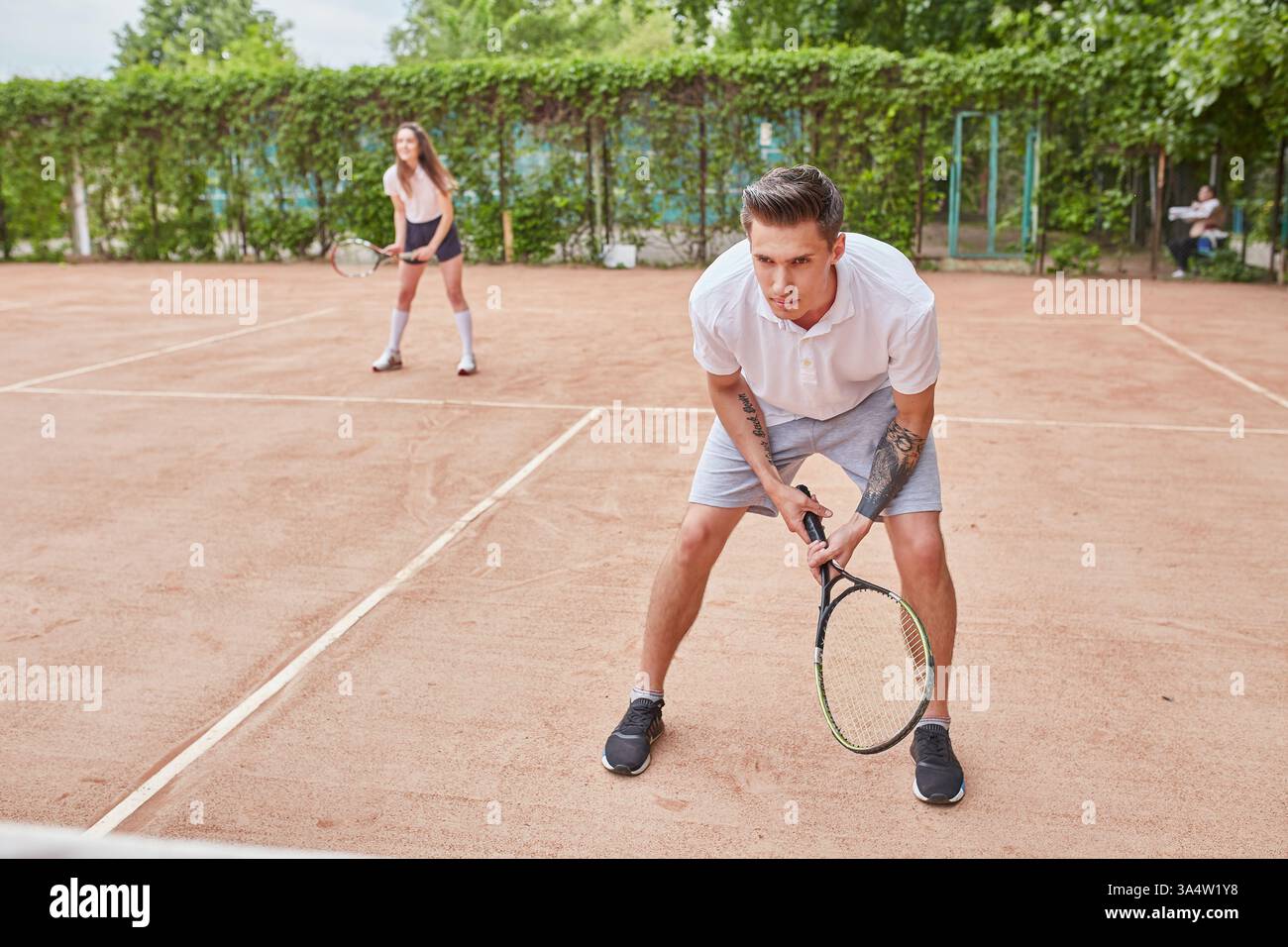 A young man in a ready position holding a tennis racket, preparing for ...