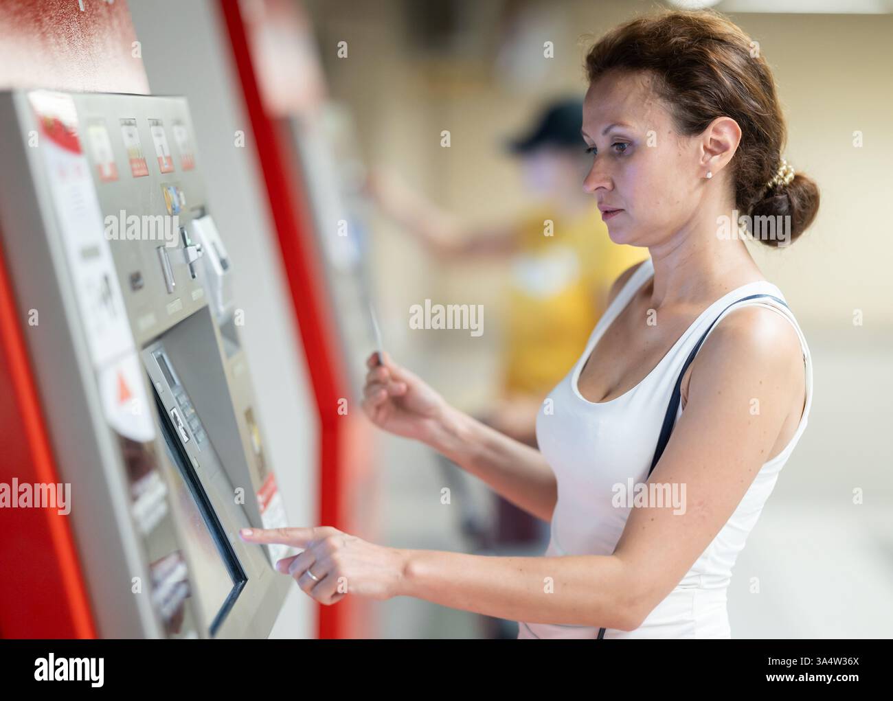 Adult woman using ticket machine at station Stock Photo - Alamy