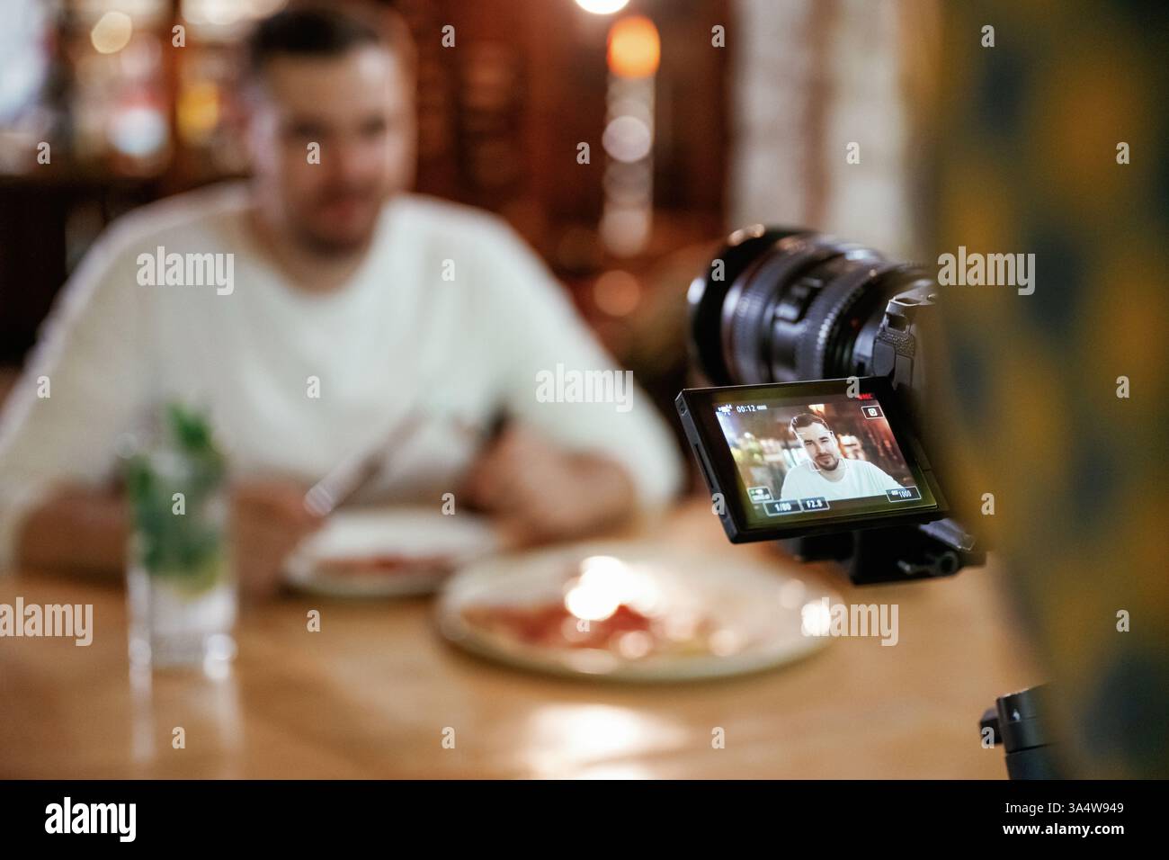 Camera is filming him. Man is sitting in the restaurant and eating a ...