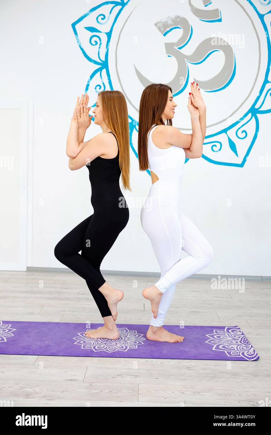 Two women practicing yoga together in a studio Stock Photo