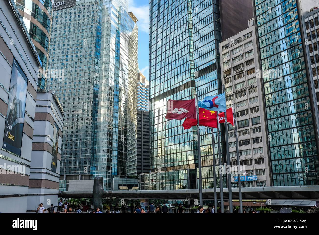 Flags flutter next to the Hong Kong stock exchange, surrounded by glass-fronted skyscrapers. Stock Photo