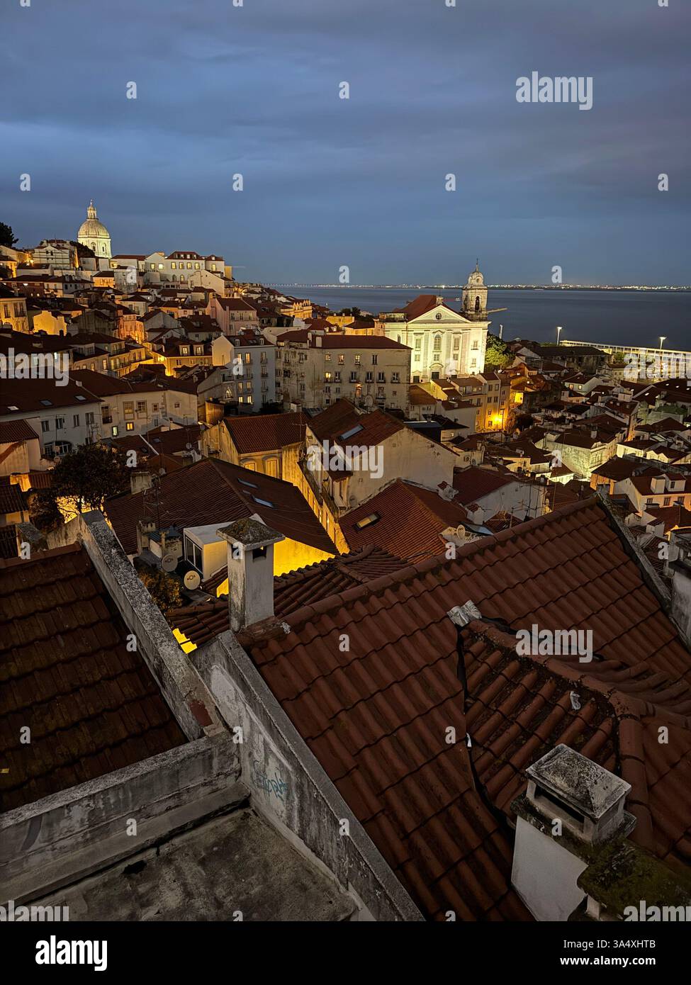An evening view from the Miradouro das Portas do Sol, looking across Lisbon's Alfama district towards the Igreja de Santo Estêvão and other landmarks. - Smartphone Captured Stock Image