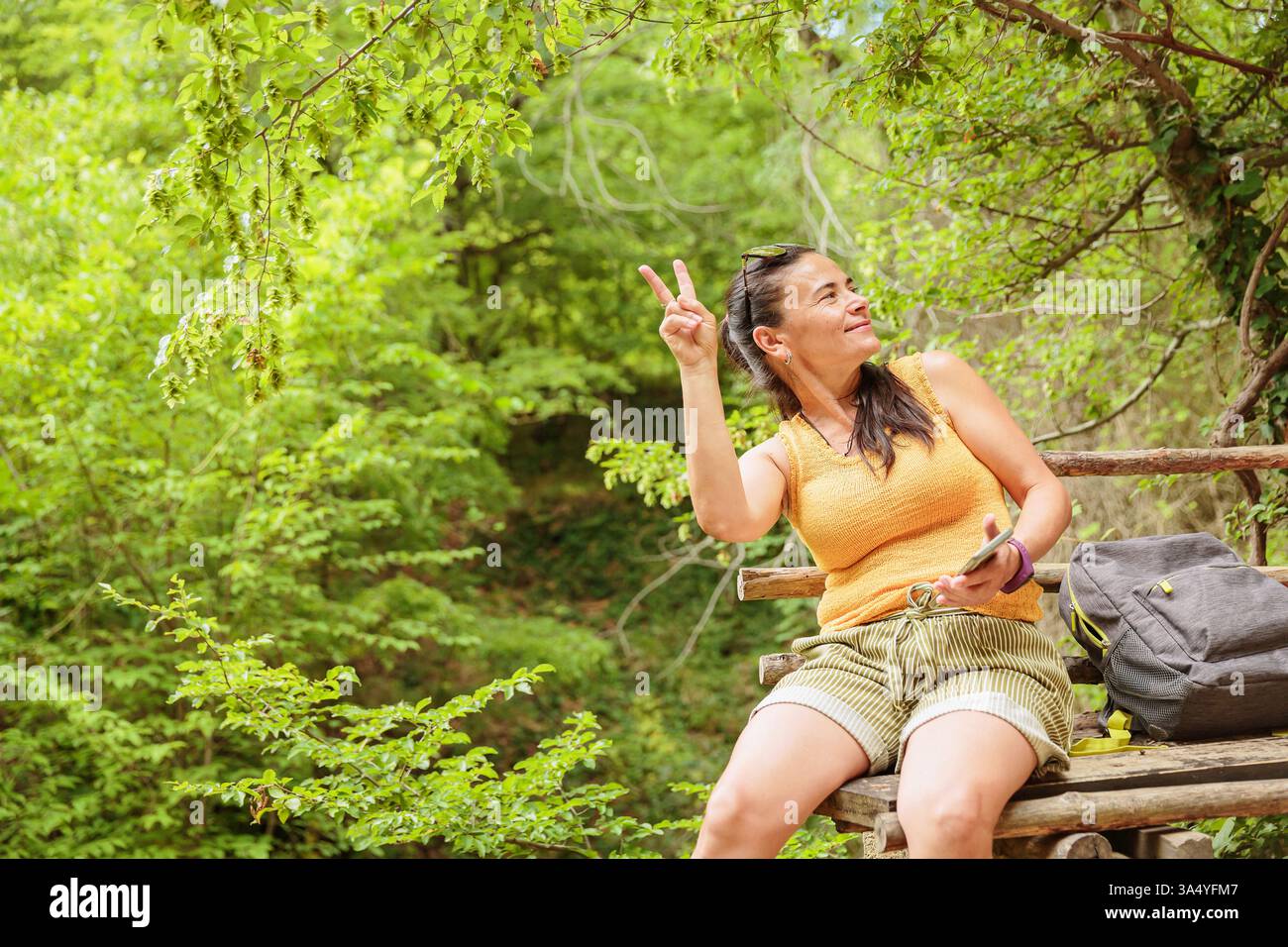 Woman sitting on wooden bench and using smartphone Stock Photo