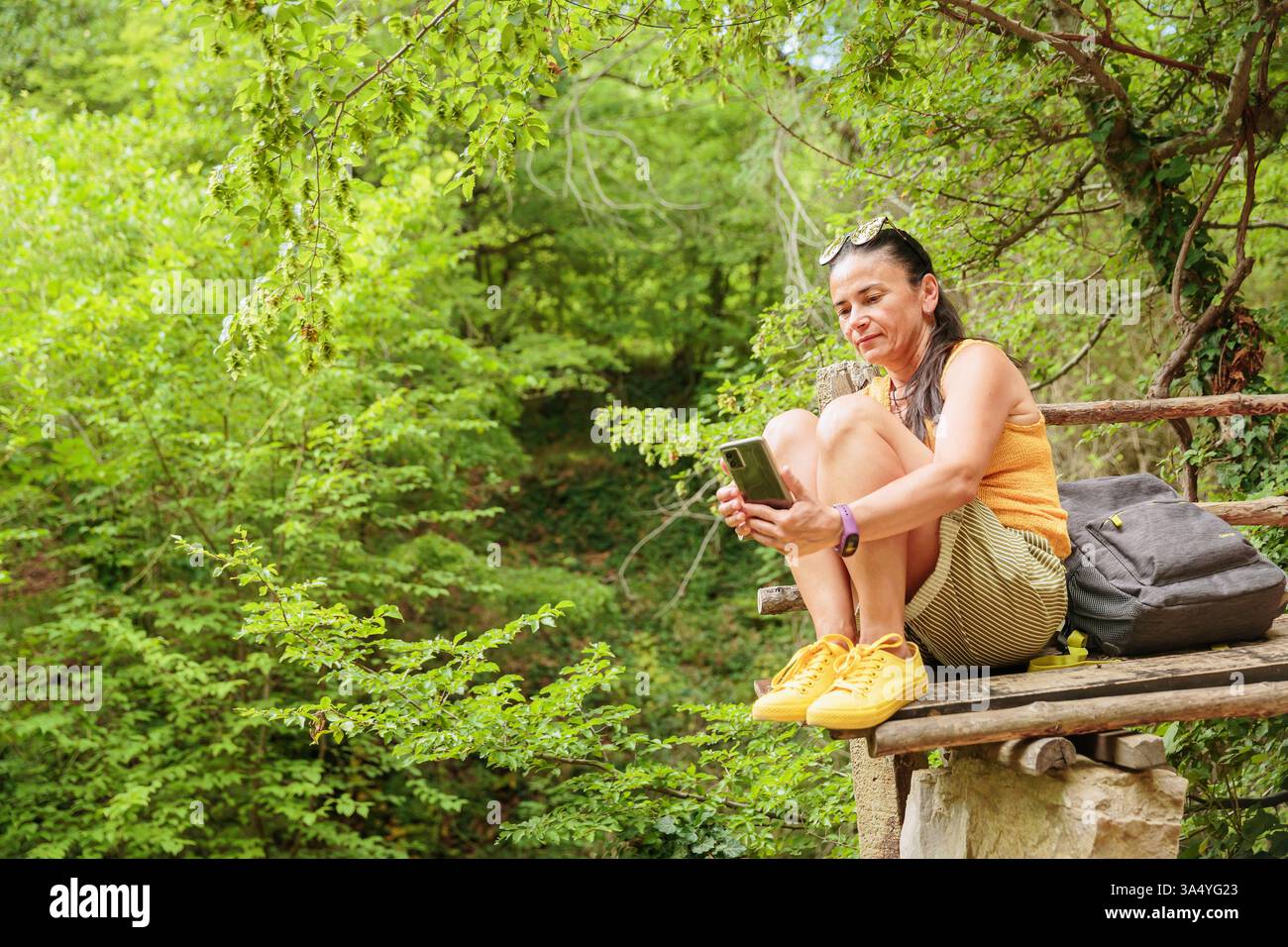 Woman using smartphone for pathfinding in forest Stock Photo