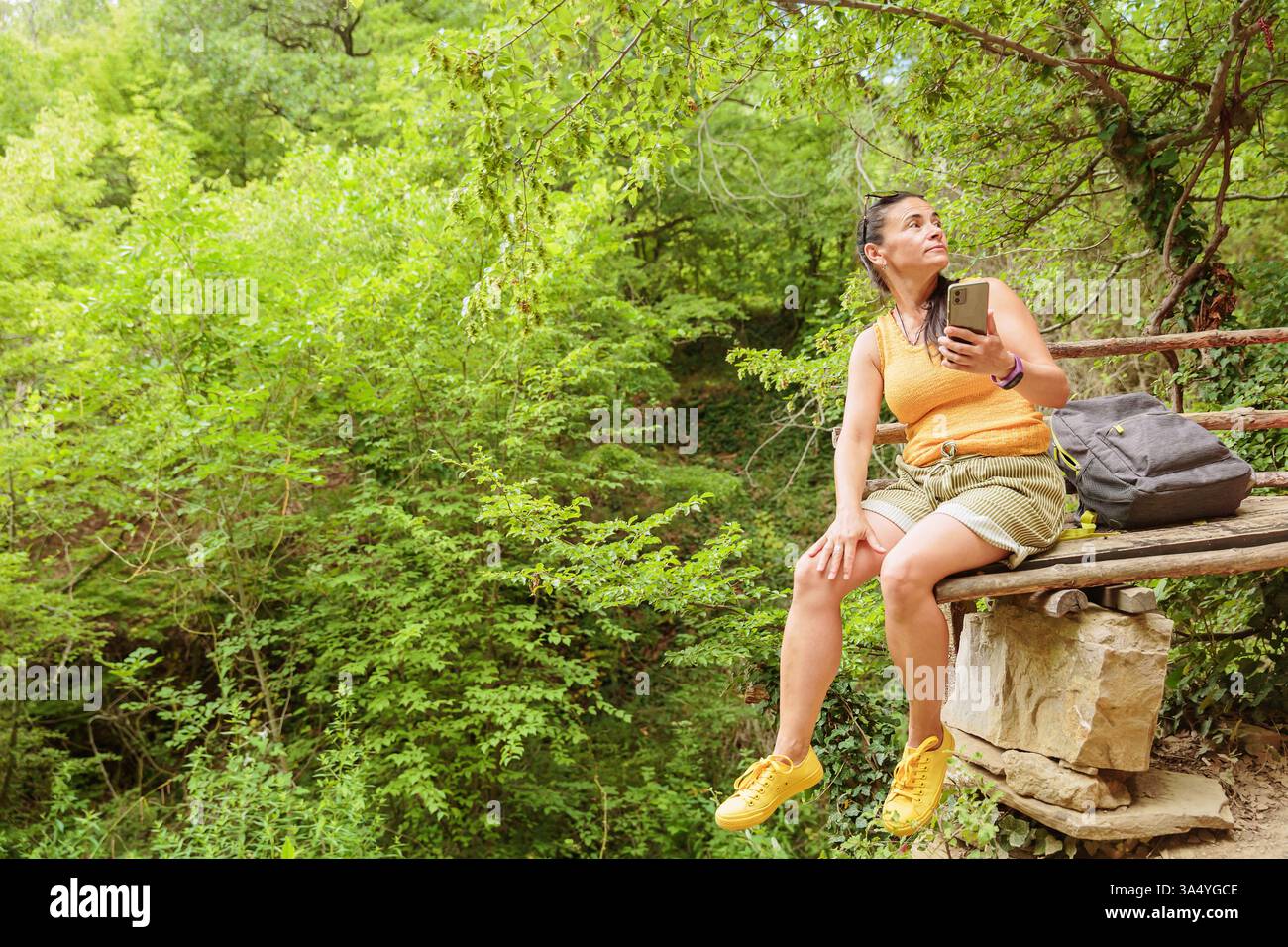 Woman using smartphone for pathfinding in forest Stock Photo