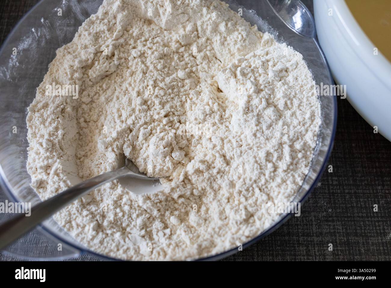 Closeup of plain flour in a bowl with a spoon Stock Photo