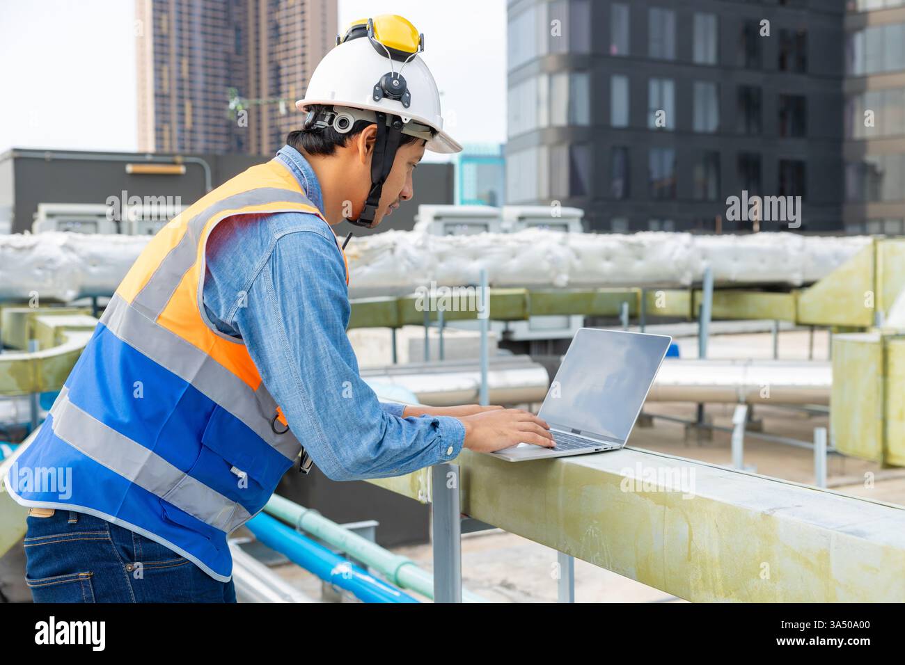Male engineer checks oil and water supply systems on a rooftop ...