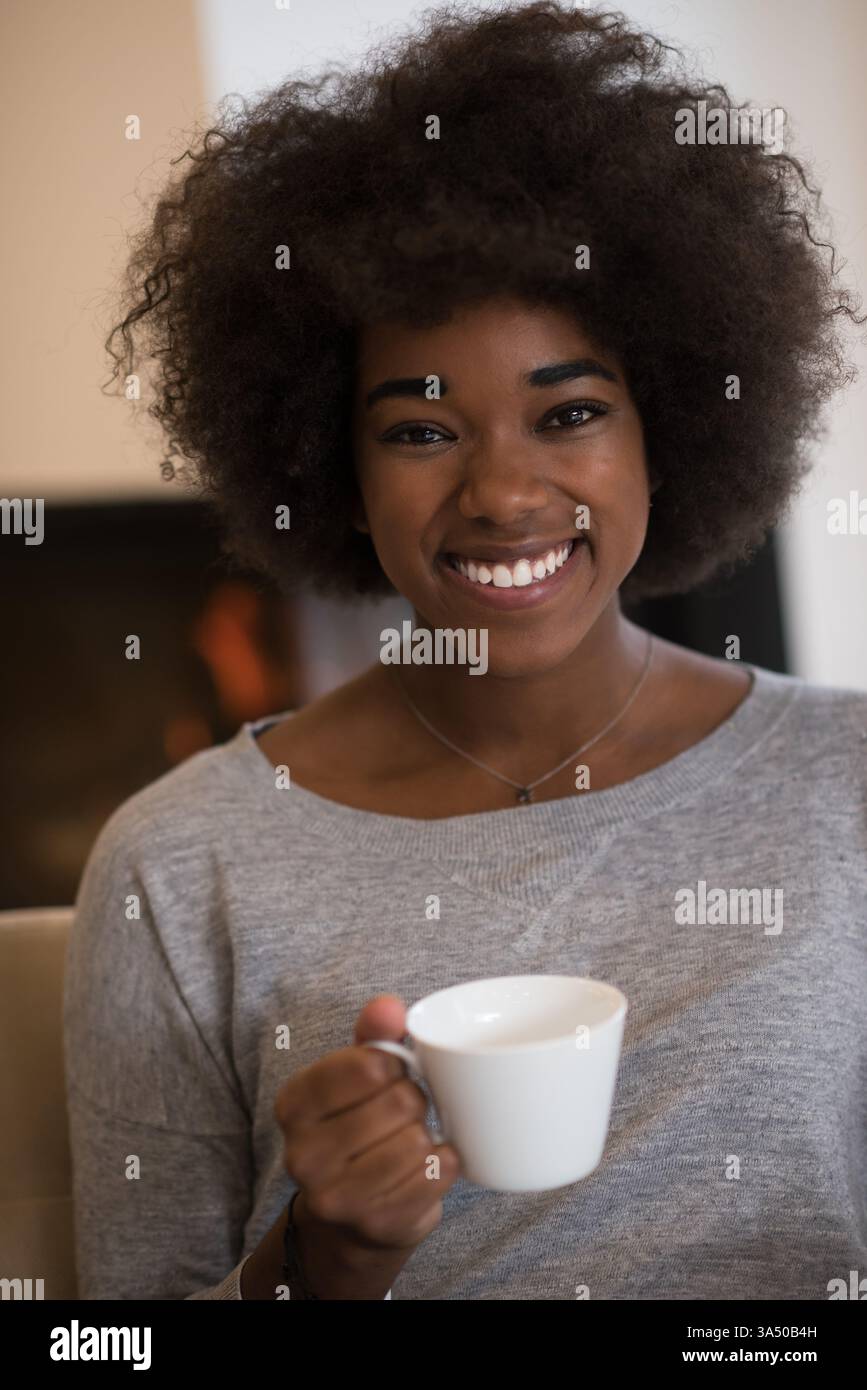 African American woman with an afro holds a coffee cup at home, smiling ...