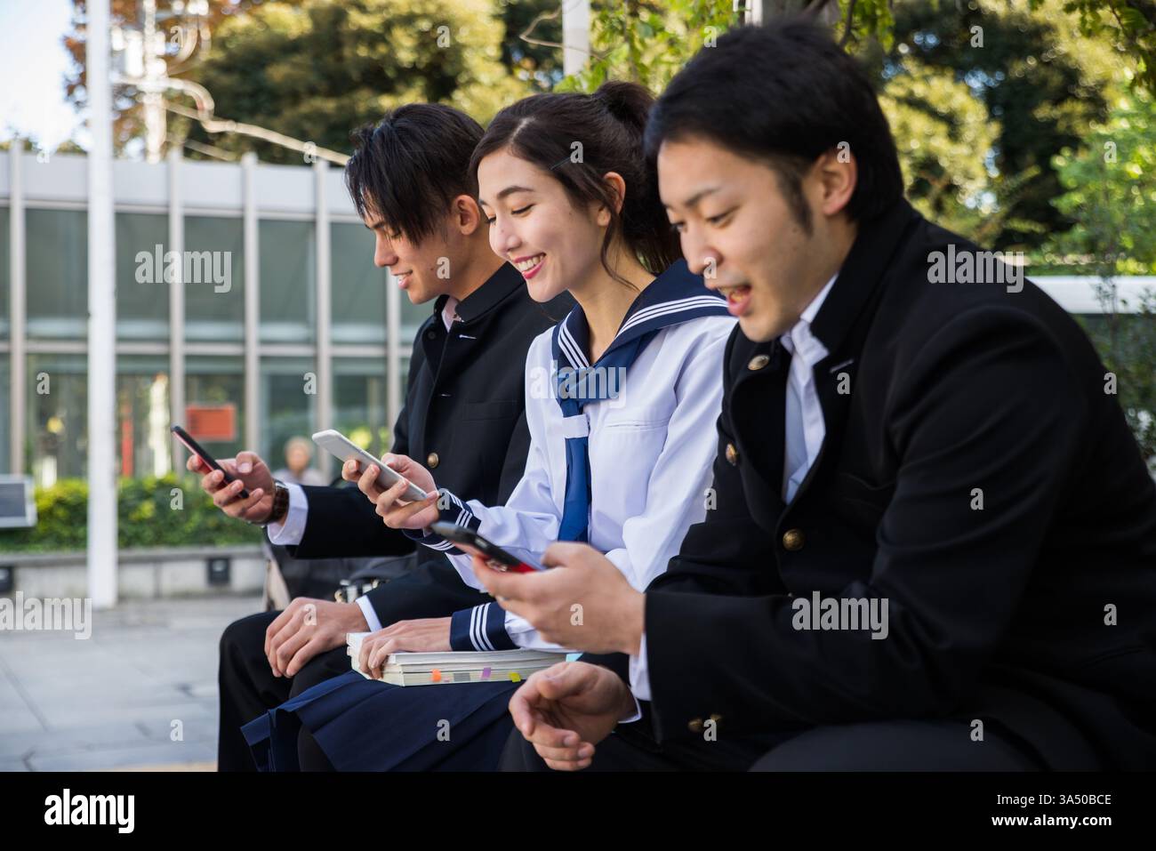 Cheerful Asian female student having fun using smartphones with male ...