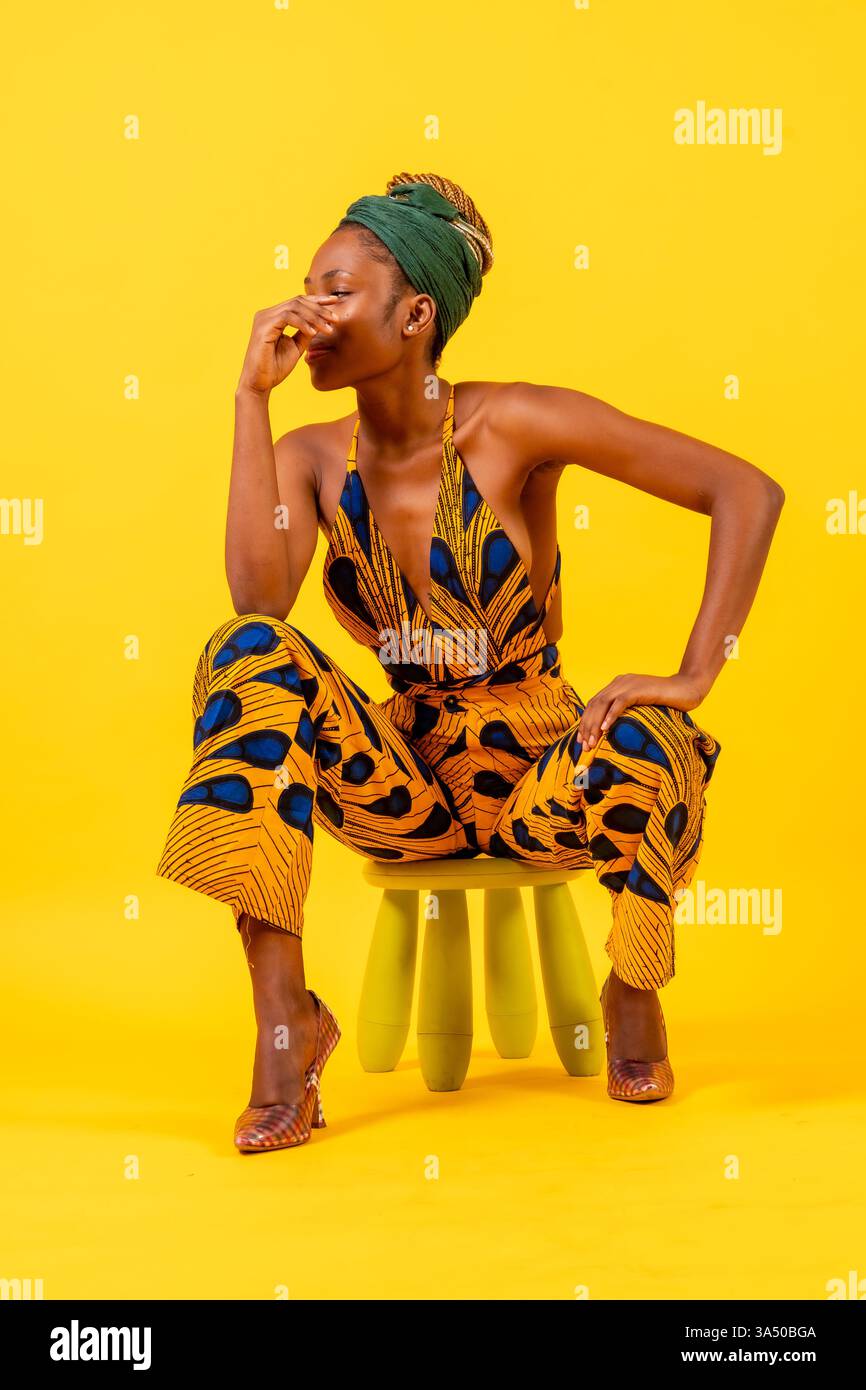 Young African woman in a traditional dress on a bright yellow ...