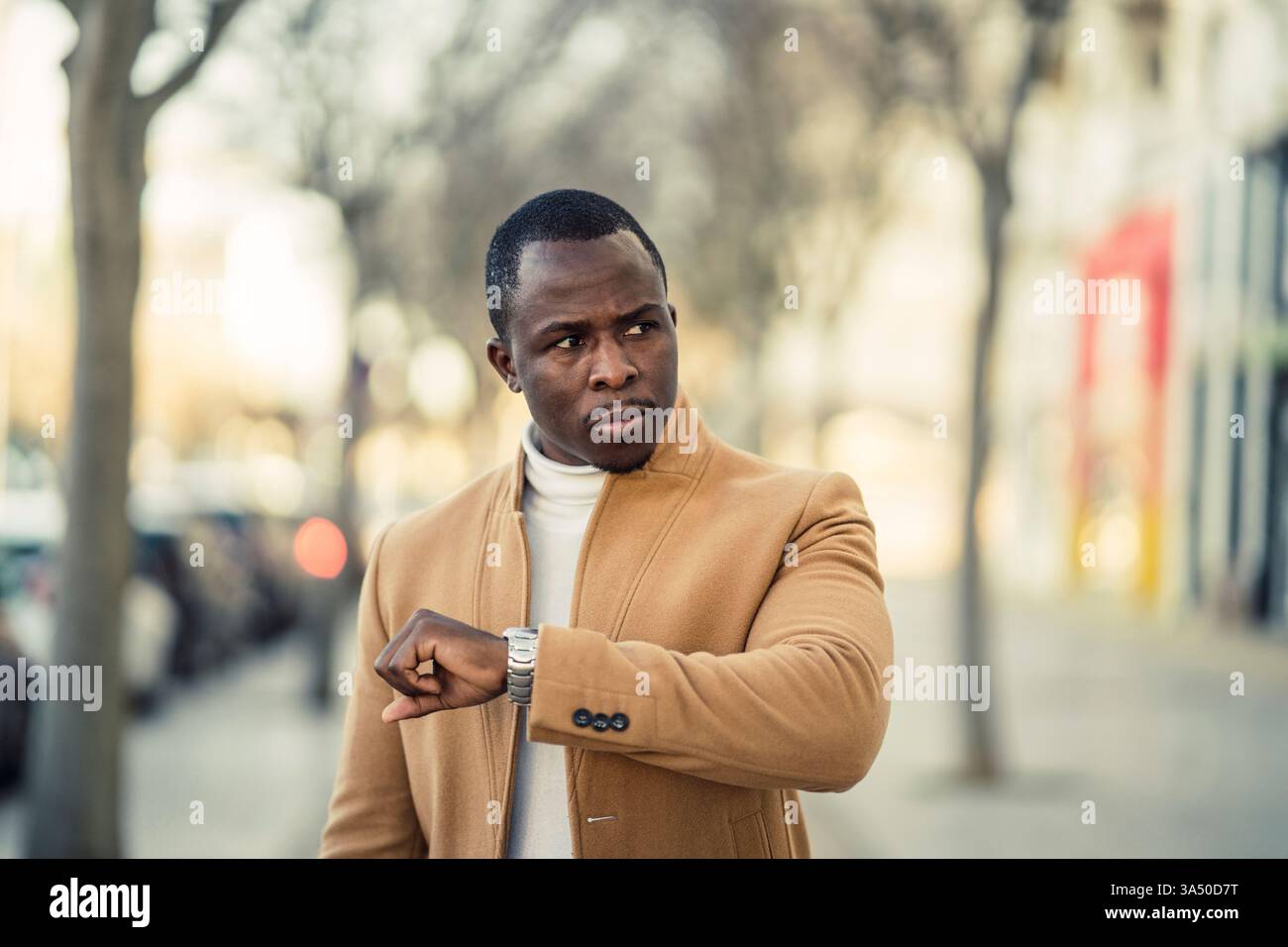 Serious African American man checking time on wristwatch looking away ...