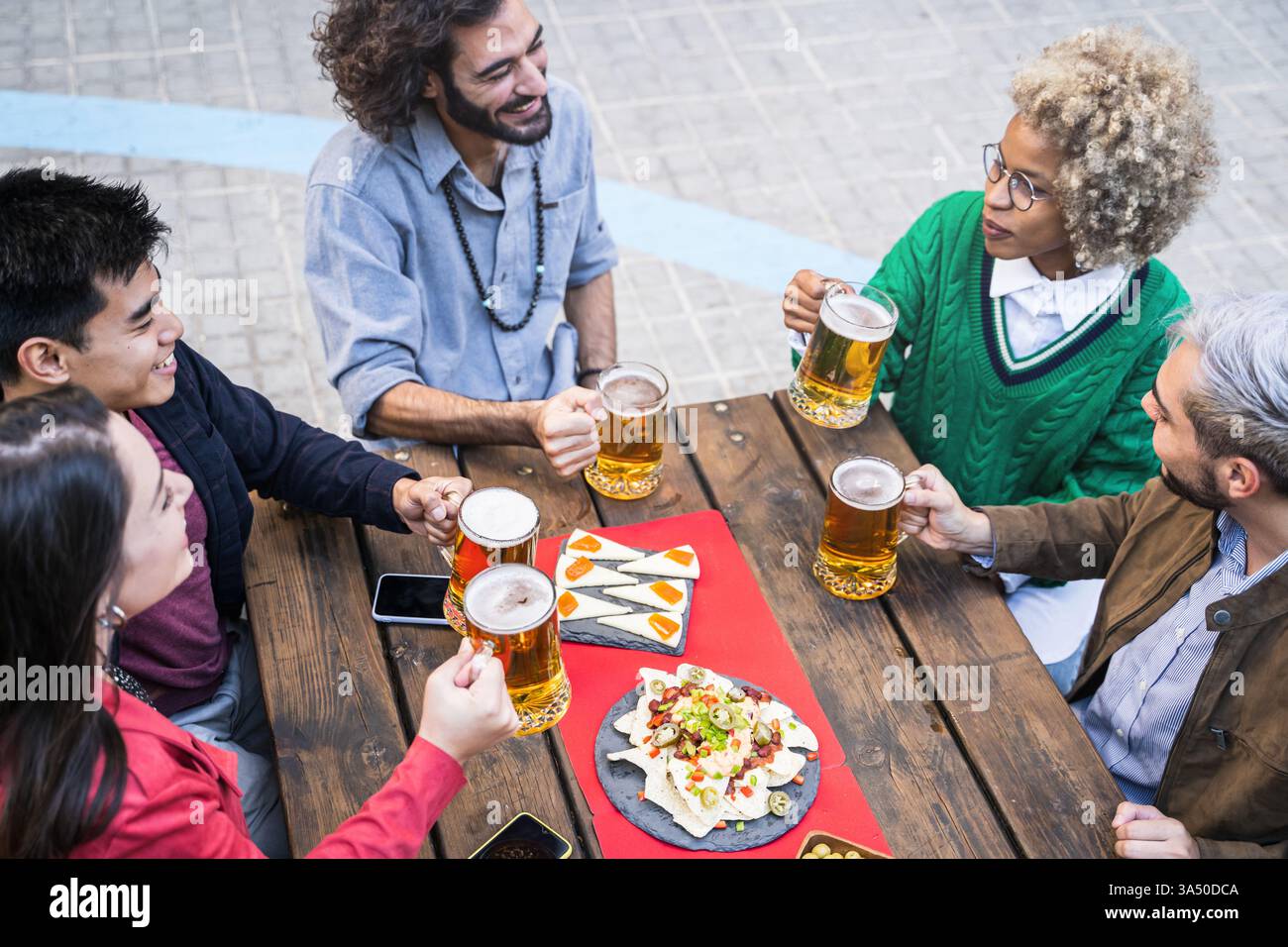 Group of diverse male and female friends sitting at table drinking beer ...