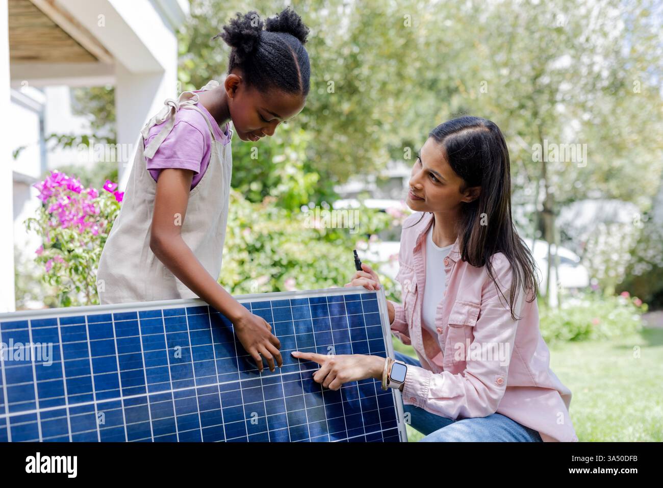 Mother and daughter exploring solar panel technology in garden, learning together Stock Photo