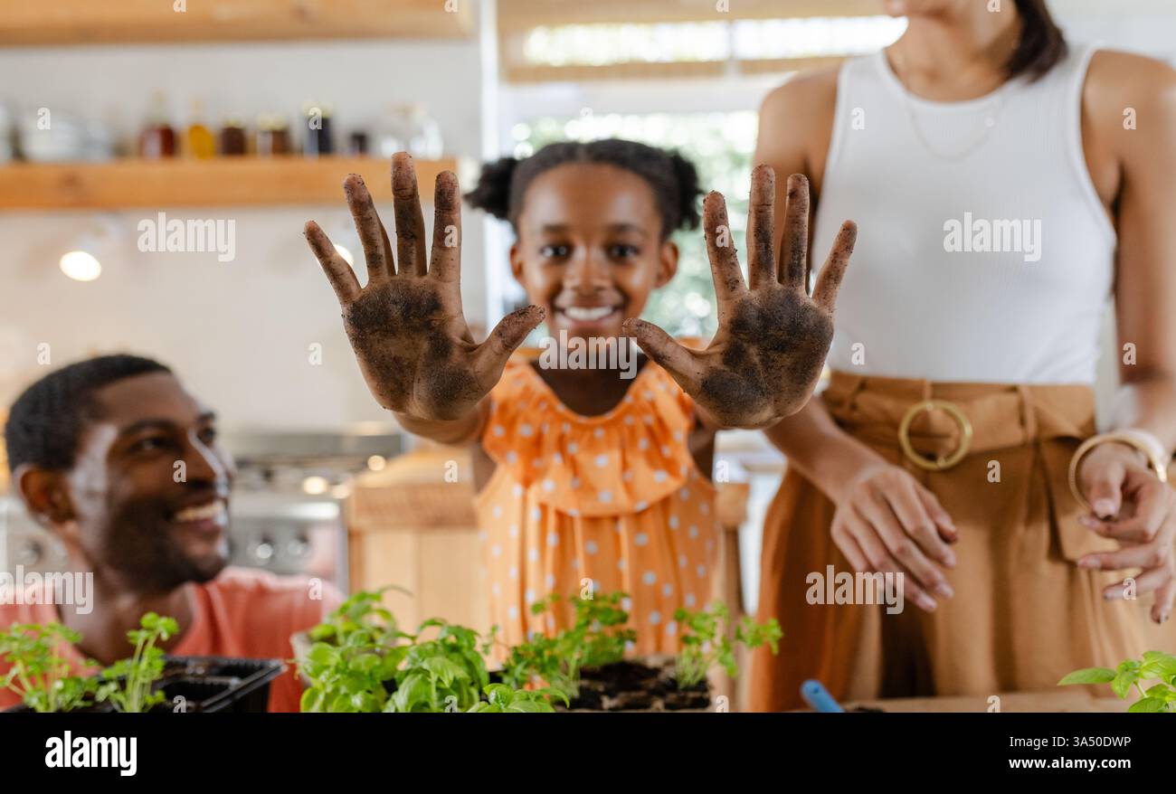 African American girl showing dirty hands while gardening with family at home Stock Photo