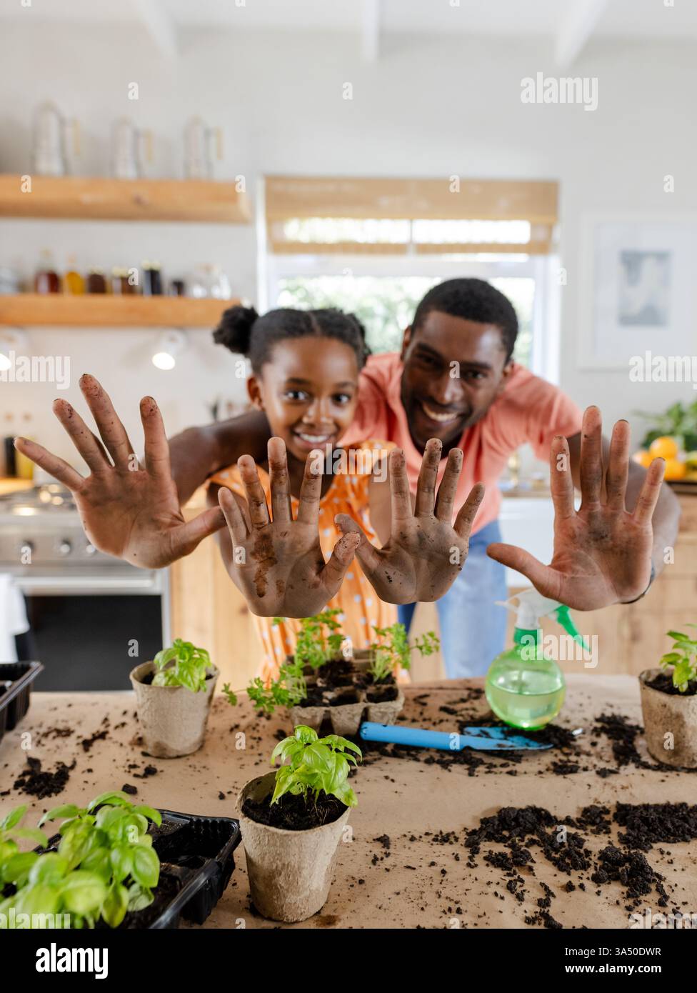 Father and daughter showing muddy hands while gardening together in kitchen Stock Photo