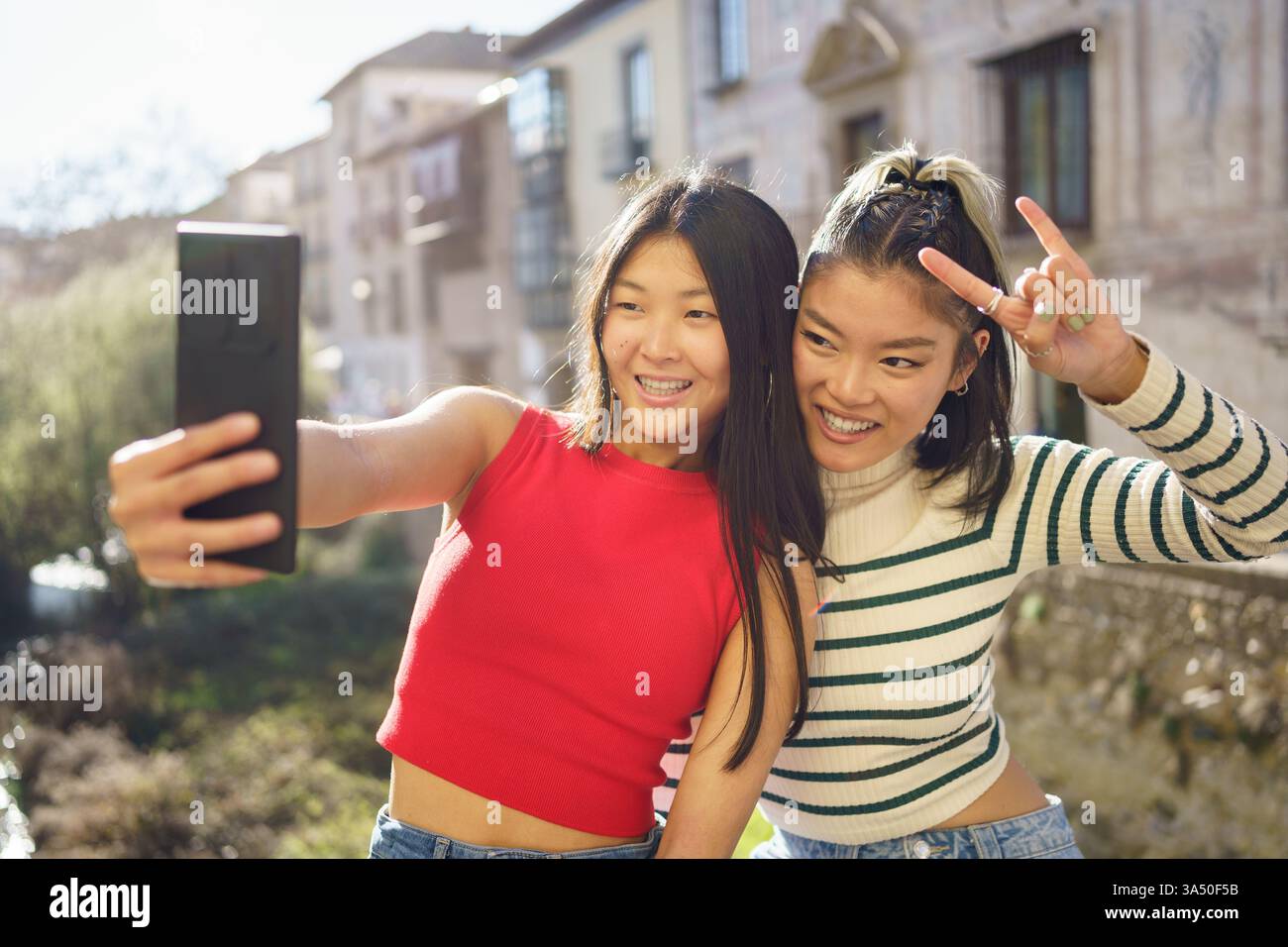 Happy Asian girlfriends in casual clothes smiling and looking at screen ...