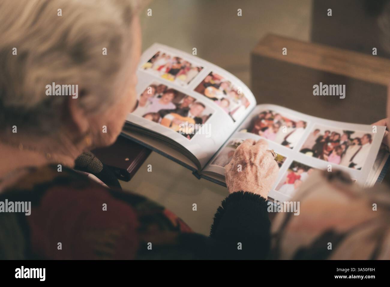 Hispanic senior woman looking at family photos from photo album at home ...