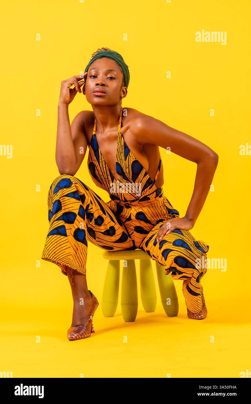 Portrait of a young African woman in traditional costume seated against ...