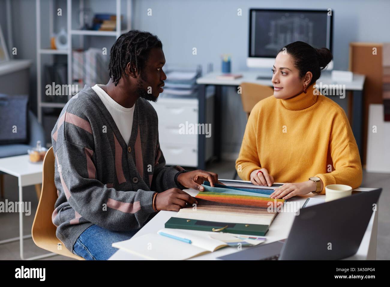 Black male and mixed-race female designers working together while ...
