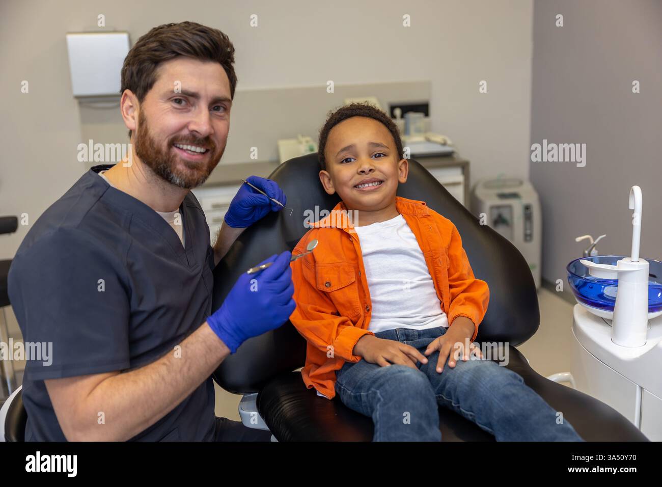 Dentist and patient share a happy smile after treatment. Indoor dental clinic setting with a positive, healthy vibe. Ideal for healthcare and dental care communications. Stock Photo