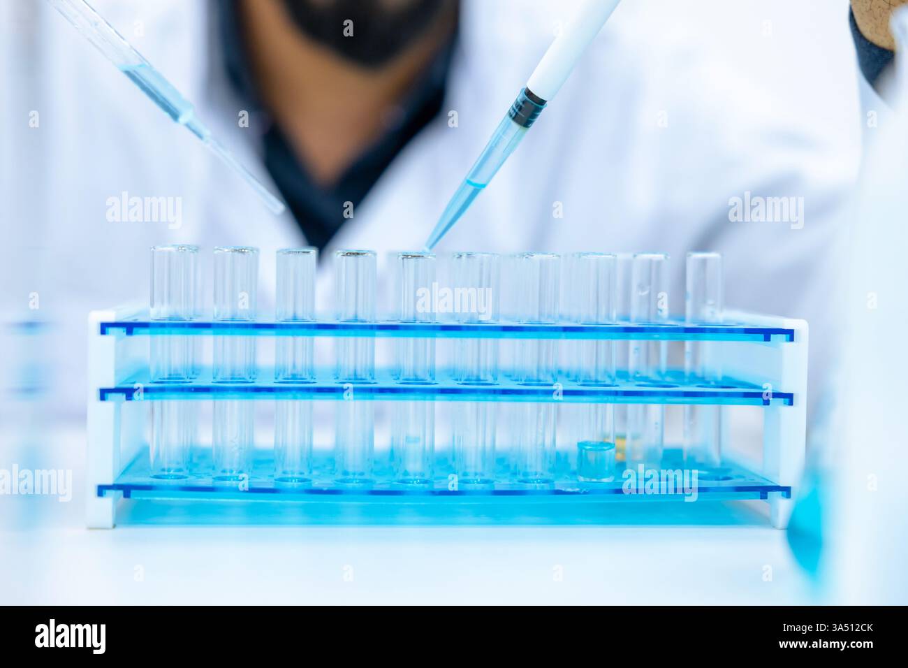 Unrecognizable male scientist in a laboratory uses a pipette and glass ...