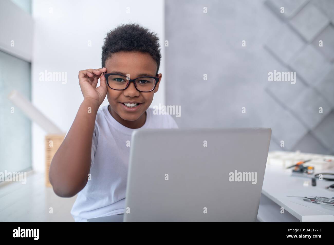 A connected teen sits at a laptop, looking engaged with the screen. The indoor setting conveys youth lifestyle and technology use. Ideal for articles about digital hobbies, online learning, and student tech. Stock Photo