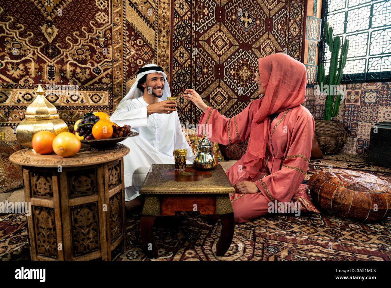 Young Emirati couple in a Dubai cafe, wearing kandura and abaya ...