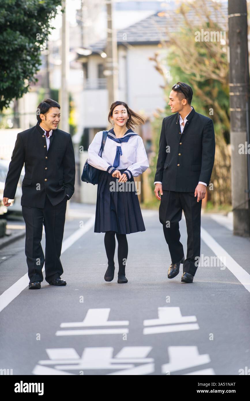 Cheerful Asian female student holding bag having fun walking on street ...
