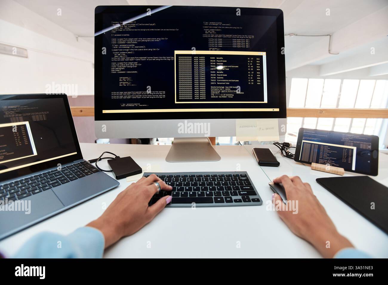 First-person view of a female software developer coding on a computer. A focused tech workspace scene highlighting programming and software development. Great for tech industry, women in tech, and IT campaigns. Stock Photo