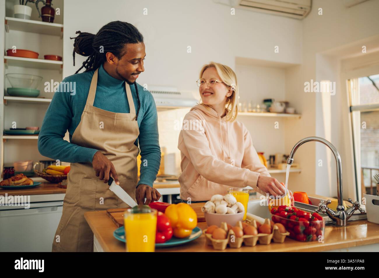 Cheerful multicultural couple cooking dinner together in a home kitchen ...