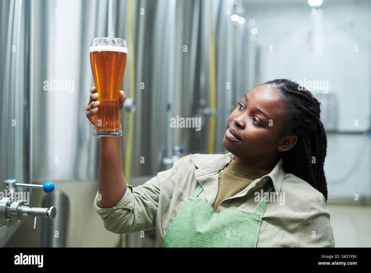 A brewery worker checks the color of beer on the production line in a ...